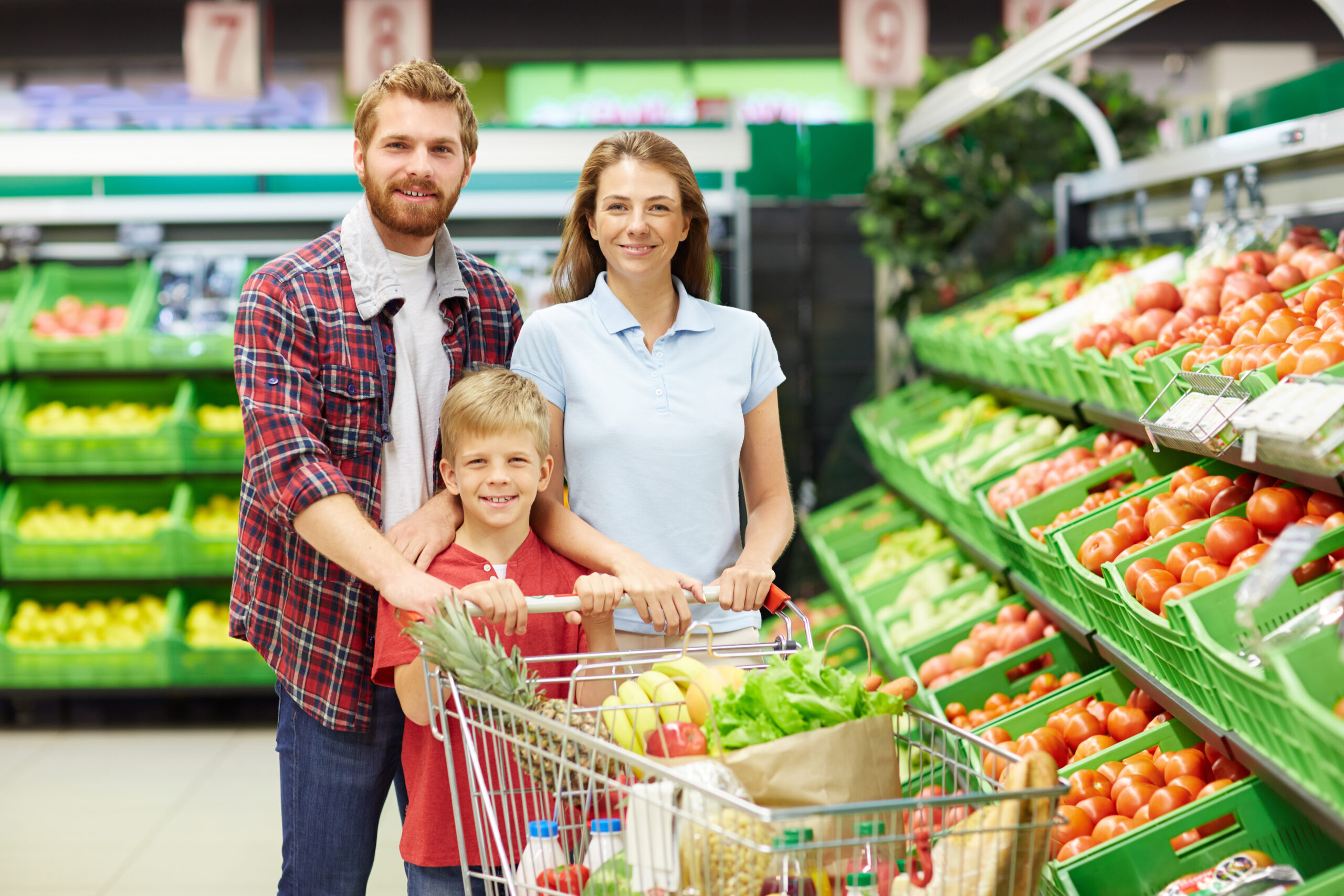 Young family with cart looking at camera in grocery store